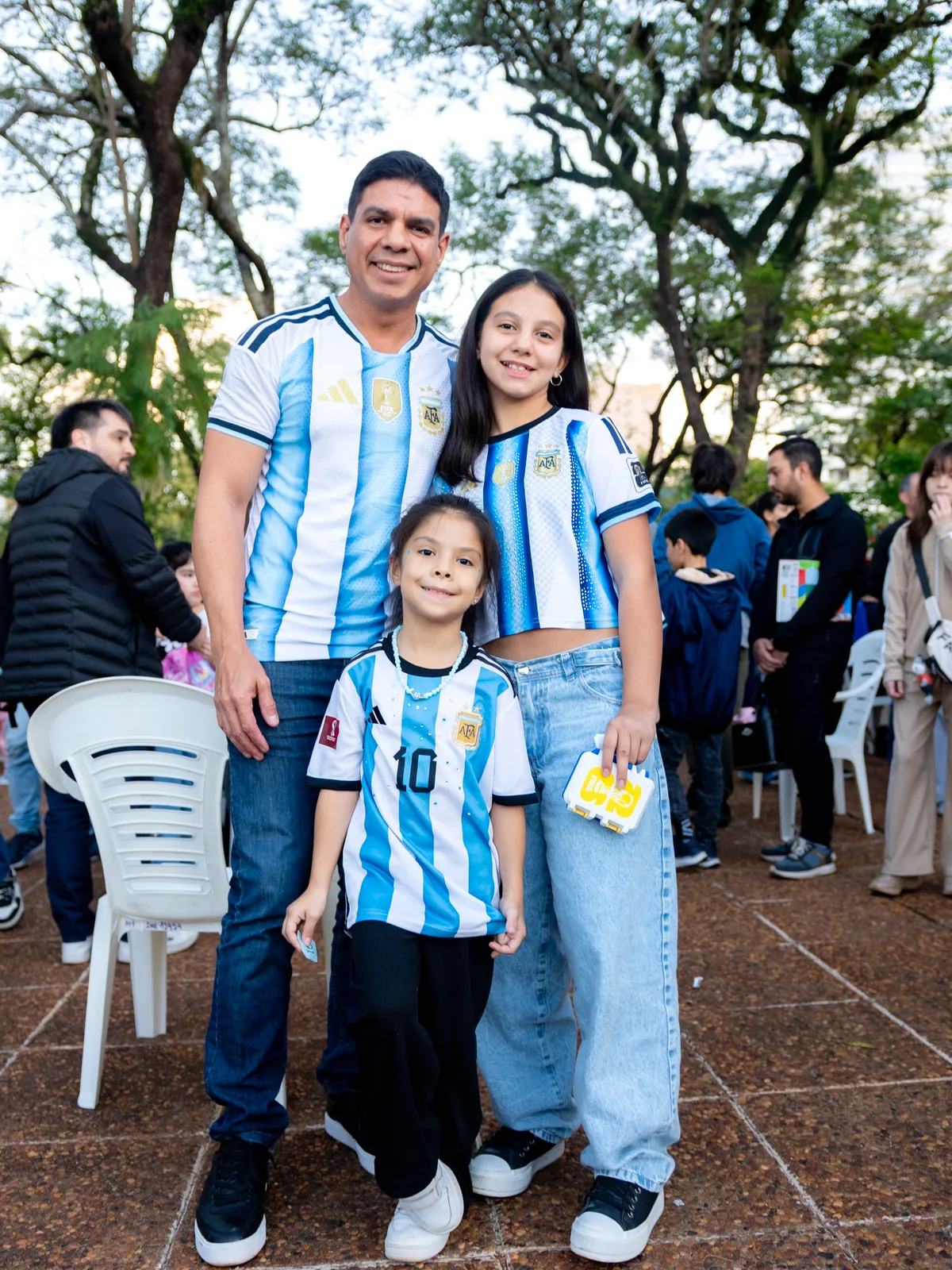 Fernando en una plaza, abrazado con dos chicas con camisetas argentinas