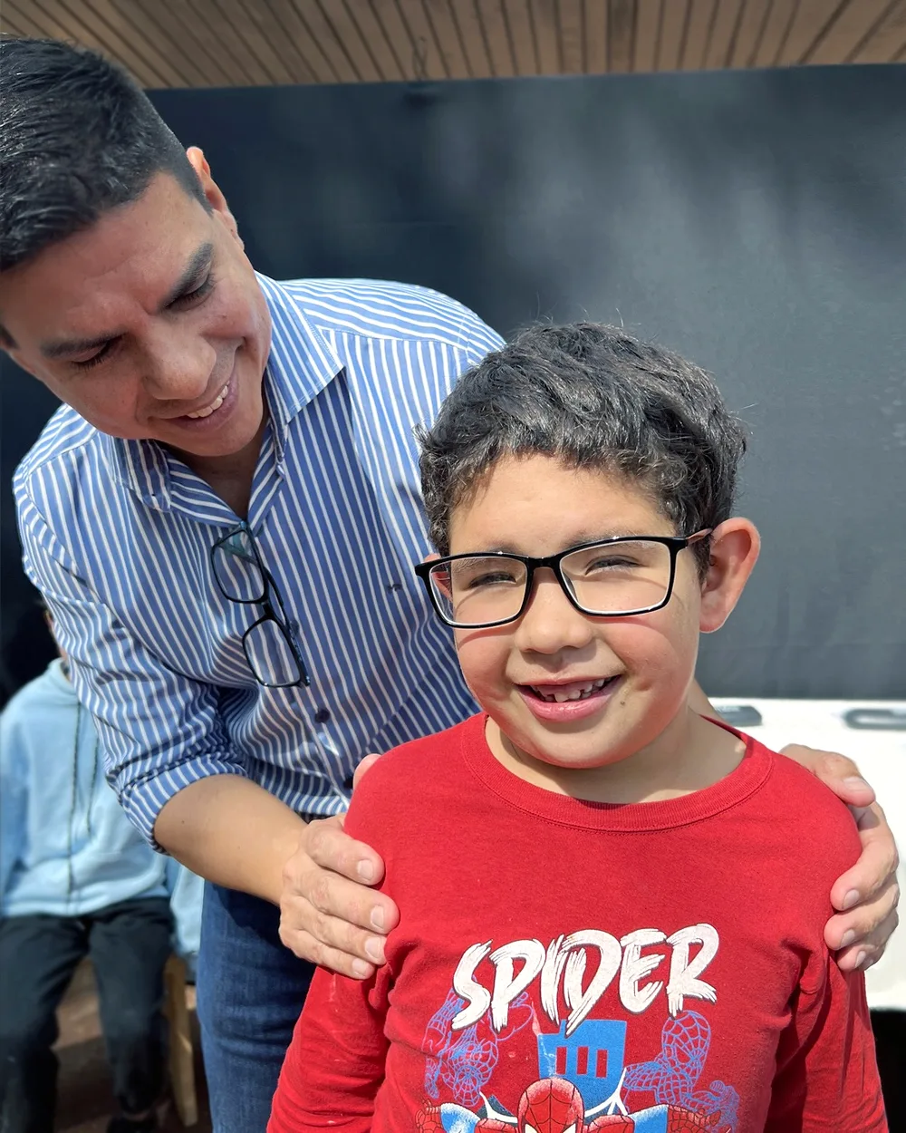 Fernando le ajusta los lentes nuevos a un nene con remera de Spider-Man